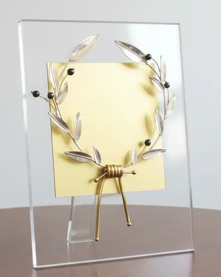 Decorative item with gold and silver design on a wooden table against a white wall