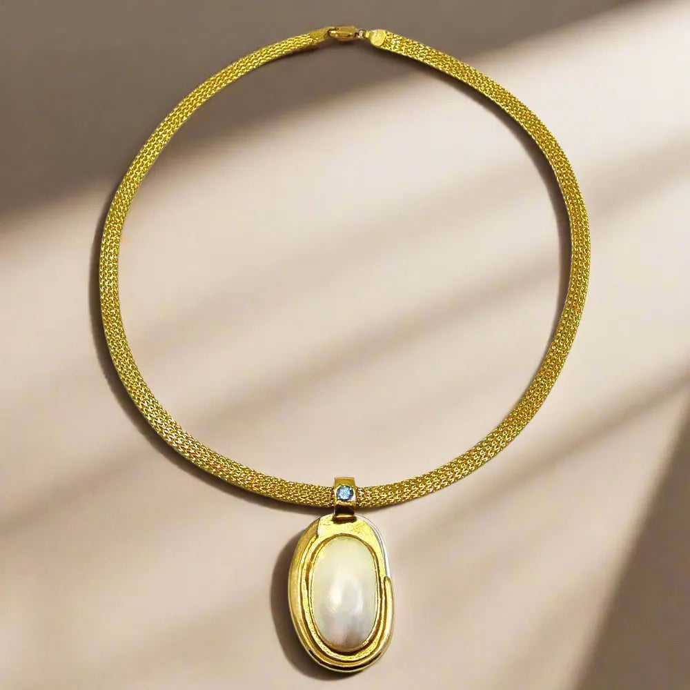 Necklace with a 18k gold medallion mother of pearl and a bleu topaz in a hand made 14k. gold chain