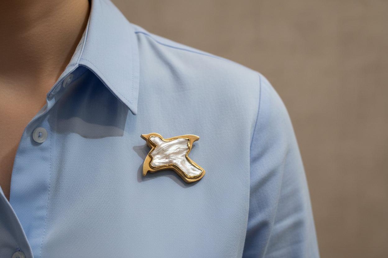 pigeon shaped pearl brooch with gold edge in a blue box on a textured white surface