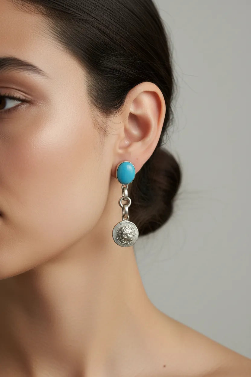 Close-up of a woman wearing turquoise earrings with a gray background