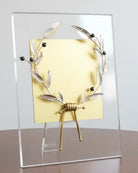 Decorative item with gold and silver design on a wooden table against a white wall