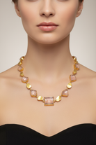 Necklace with gold and pink stones worn by a model against a neutral background