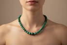 Green beaded necklace on a white fabric background
