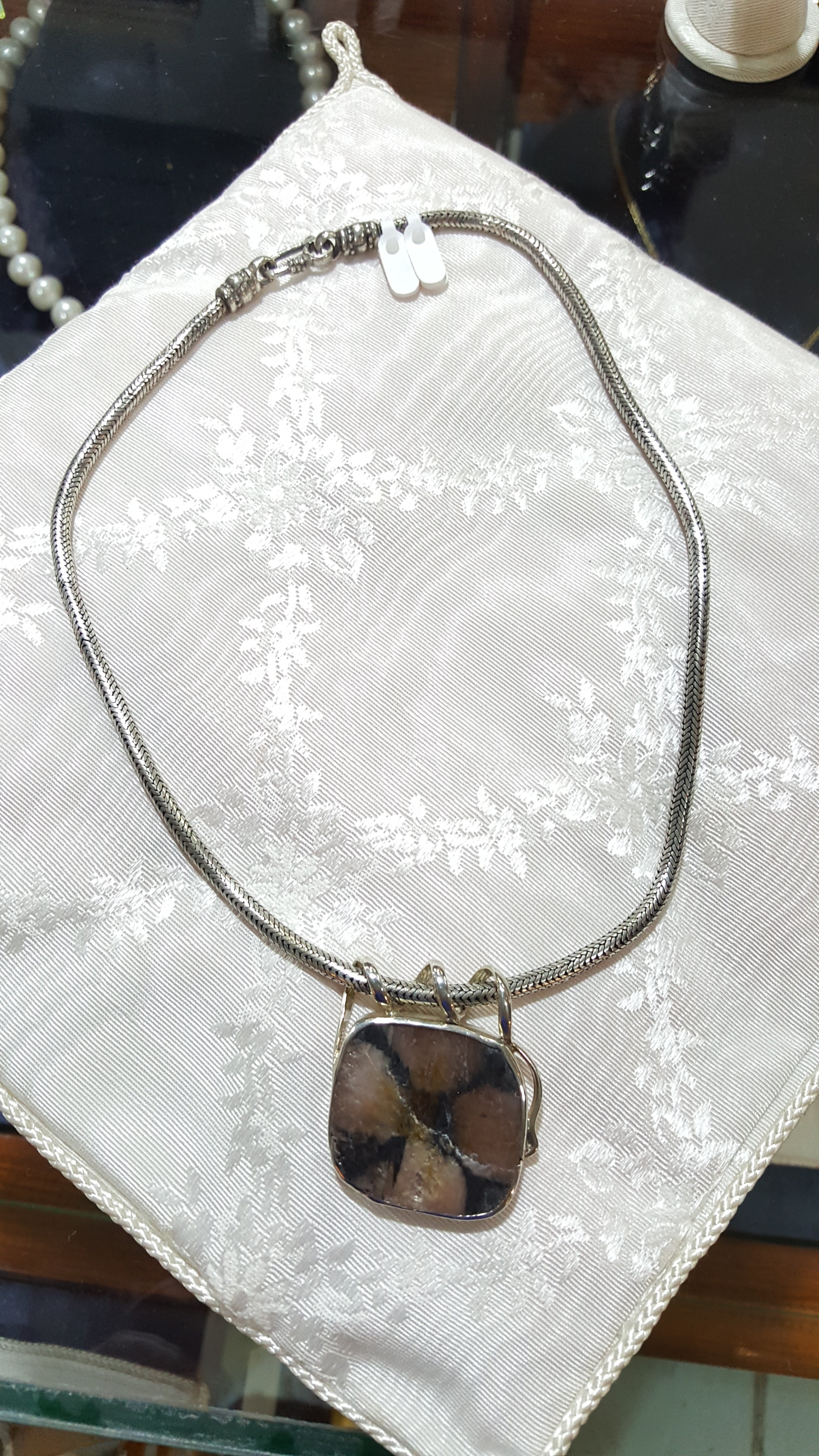 Necklace with a square pendant on a textured white surface
